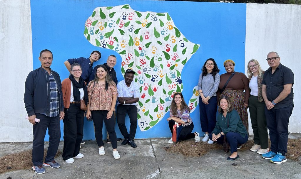 A group of people stand in front of an image showing the outlines of the African continent.